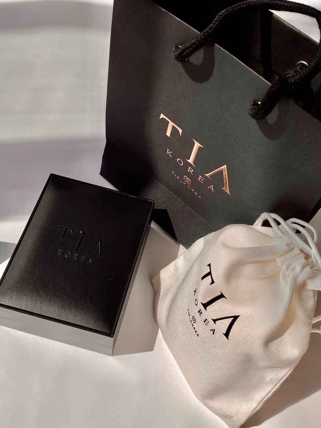 Luxury TIA Korea jewelry packaging, including a black gift bag, jewelry box, and branded pouch, perfect for gifting.